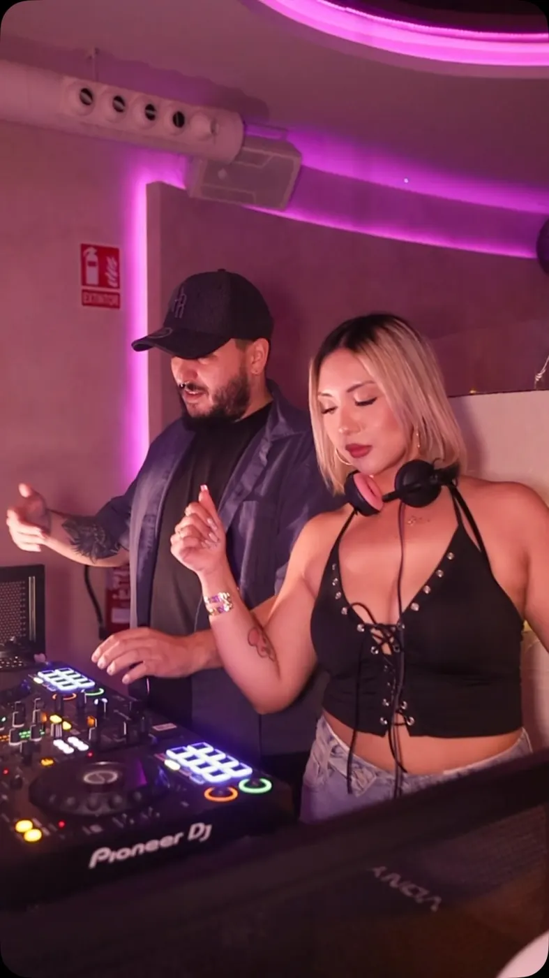 DJs pinchando en la cabina con luz morada